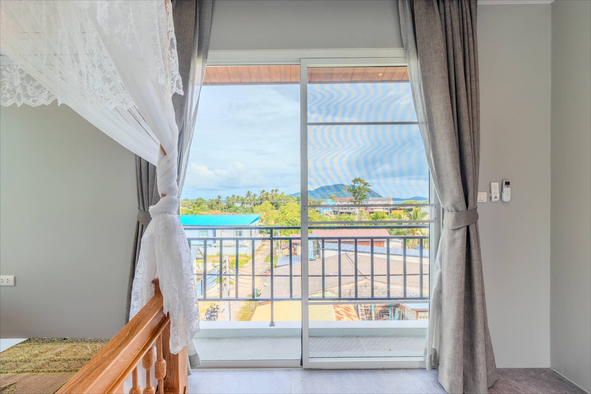 Balcony view of Rawai hills through sliding doors