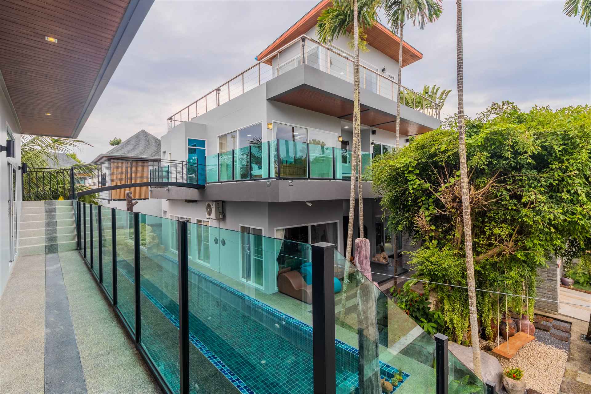 Turquoise glass-walled pool with tropical landscaping